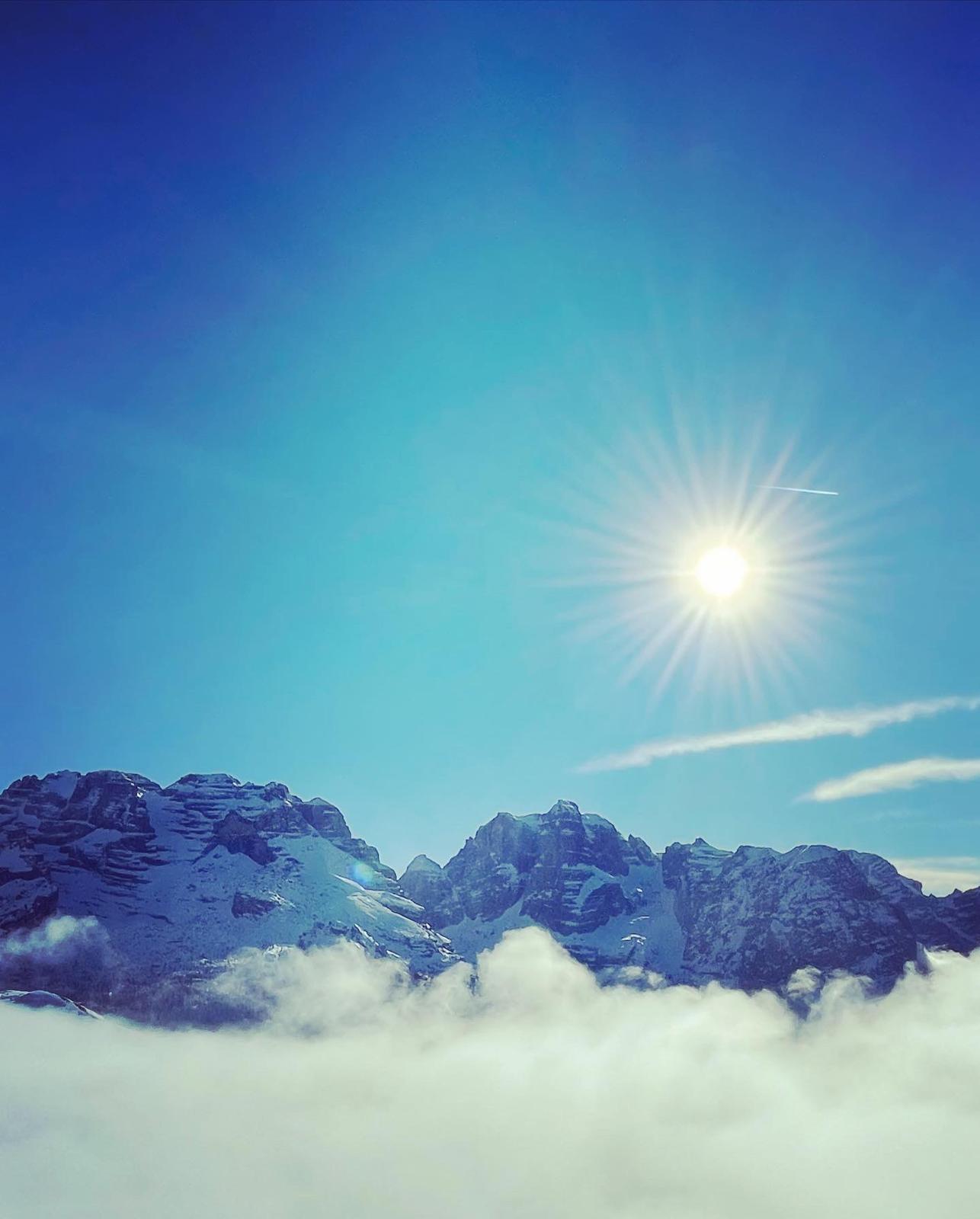 Le cime innevate del Brenta che emergono da un mare di nuvole, illuminate dal sole