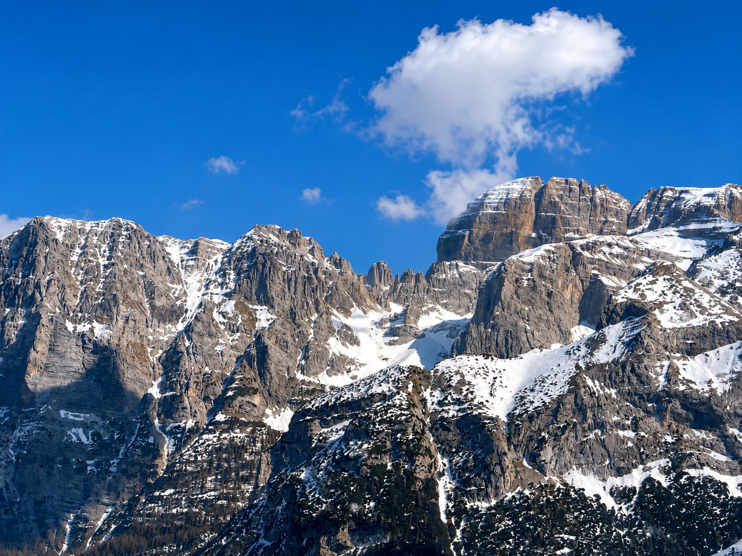 Le cime frastagliate e imbiancate delle Dolomiti di Brenta contro un cielo invernale azzurro intenso