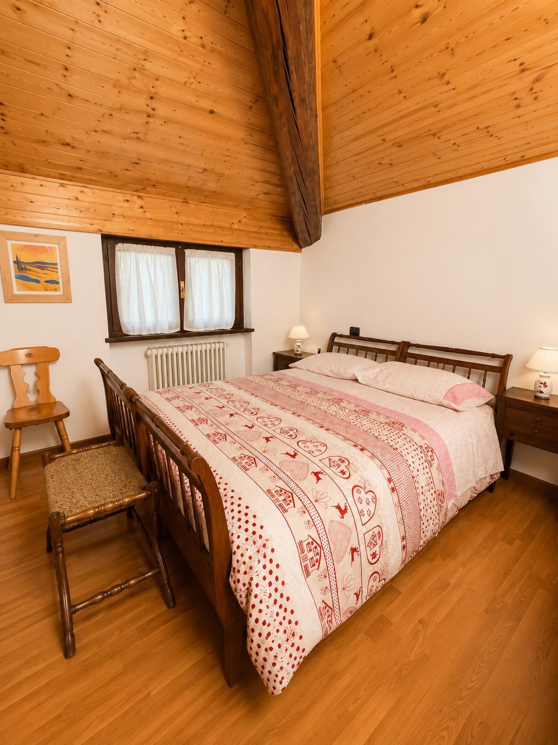 Letto matrimoniale sotto il soffitto mansardato in legno