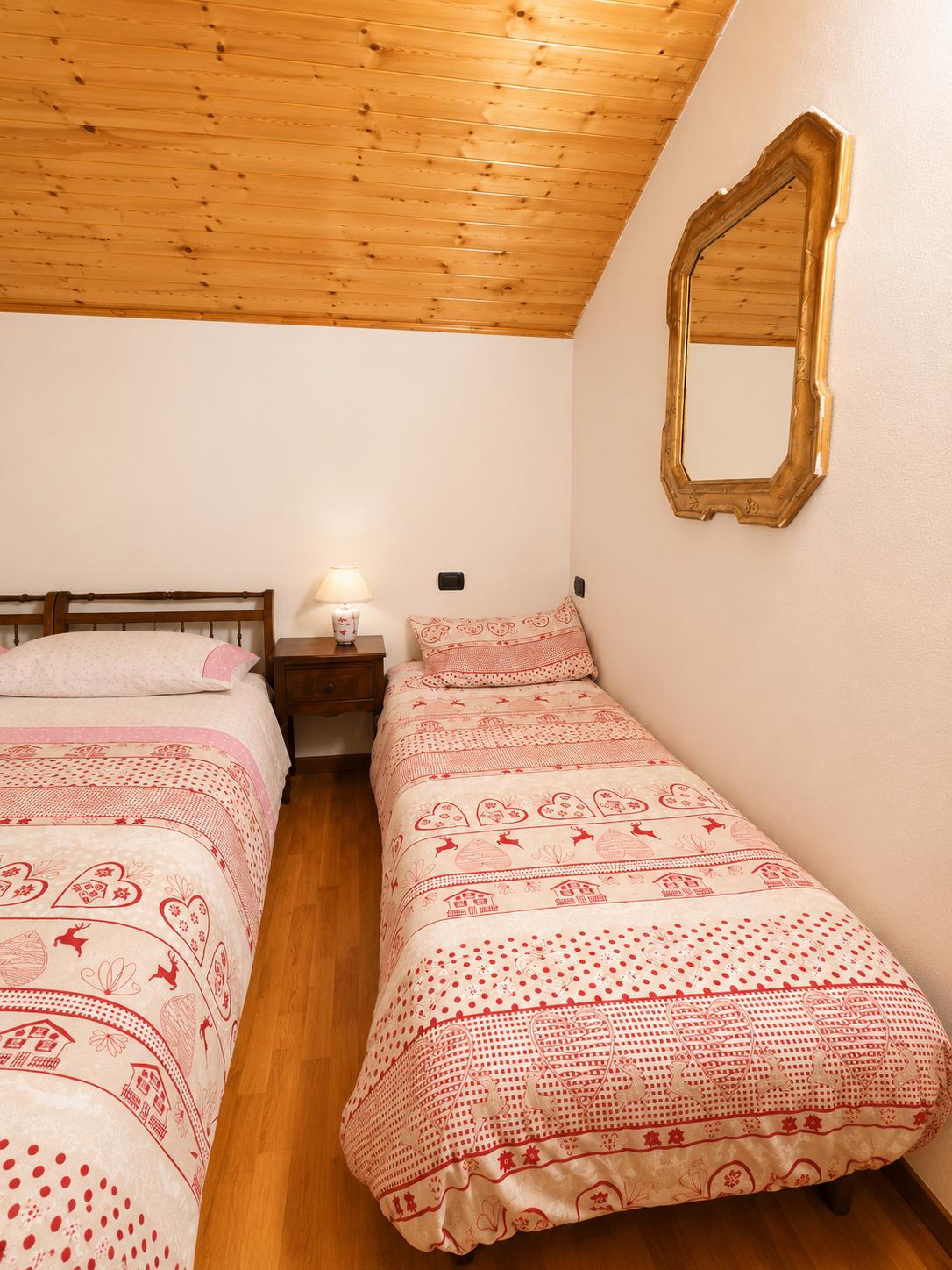 Letto singolo con biancheria in stile alpino sotto il soffitto in legno
