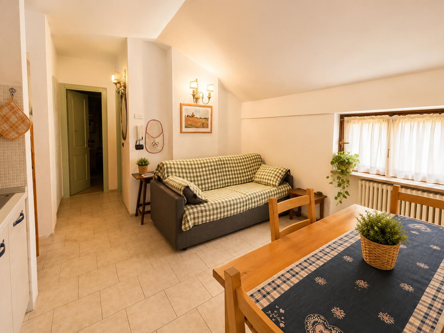 Zona giorno con divano letto, tavolo da pranzo e soffitto mansardato spiovente